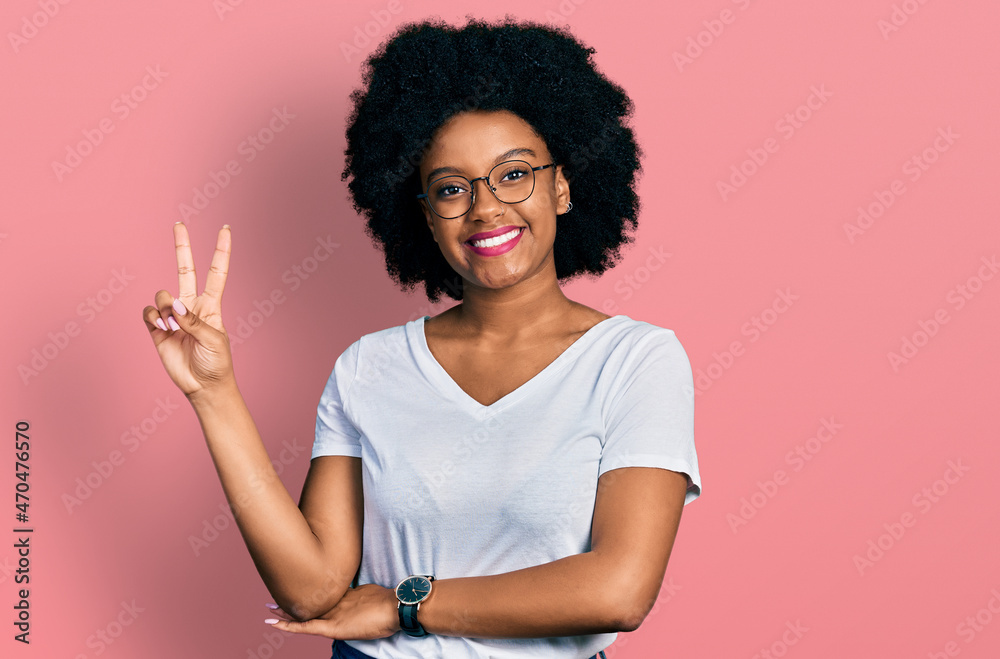 Young african american woman wearing casual white t shirt smiling looking to the camera showing fingers doing victory sign. number two. Young african american woman wearing casual white t shirt smiling looking to the camera showing fingers doing victory sign. number two.