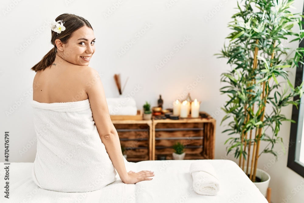 Young hispanic woman smiling confident sitting on massage table at beauty center. Young hispanic woman smiling confident sitting on massage table at beauty center.