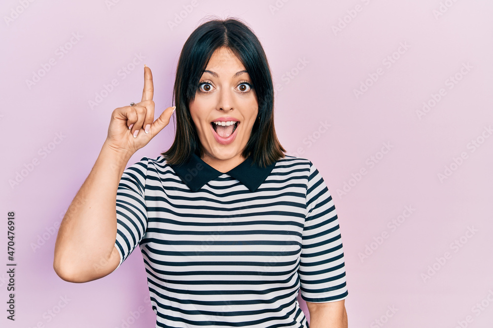 Young hispanic woman wearing casual clothes pointing finger up with successful idea. exited and happy. number one. Young hispanic woman wearing casual clothes pointing finger up with successful idea. exited and happy. number one.