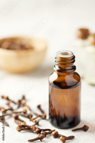 A glass bottle of clove oil and a clove on the table. Essential oil of cloves.