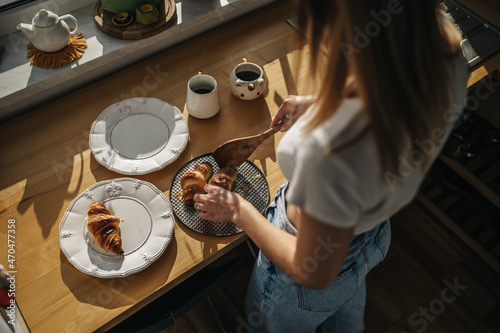 Fresh croissants on a plate. The girl puts croissants on a plate