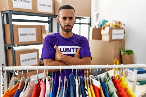 African american man wearing volunteer t shirt at donations stand skeptic and nervous, disapproving expression on face with crossed arms. negative person.