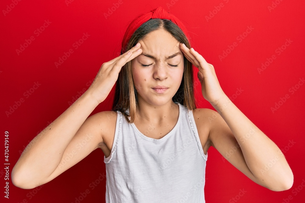 Beautiful brunette little girl wearing casual white t shirt with hand on head, headache because stress. suffering migraine. Beautiful brunette little girl wearing casual white t shirt with hand on head, headache because stress. suffering migraine.
