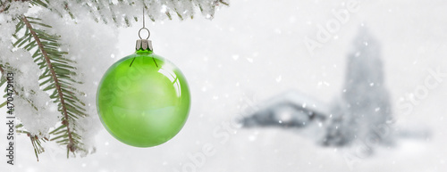 Zwei grüne Weihanchtskugeln an einem schneebedeckten Tannenzweig
