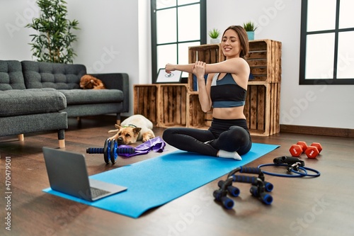 Young hispanic woman smiling confident having online stretching class at home