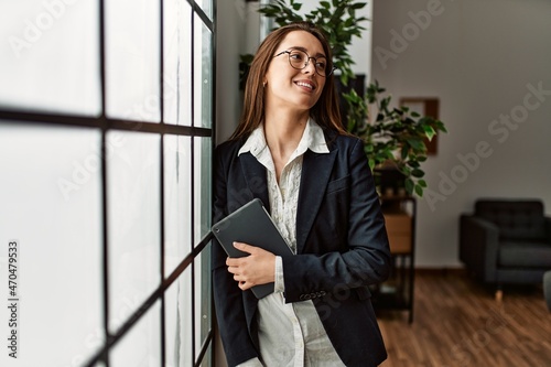 Young hispanic woman business worker holding touchpad standing at office