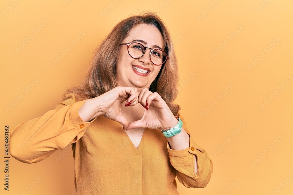 Middle age caucasian woman wearing casual clothes and glasses smiling in love doing heart symbol shape with hands. romantic concept.