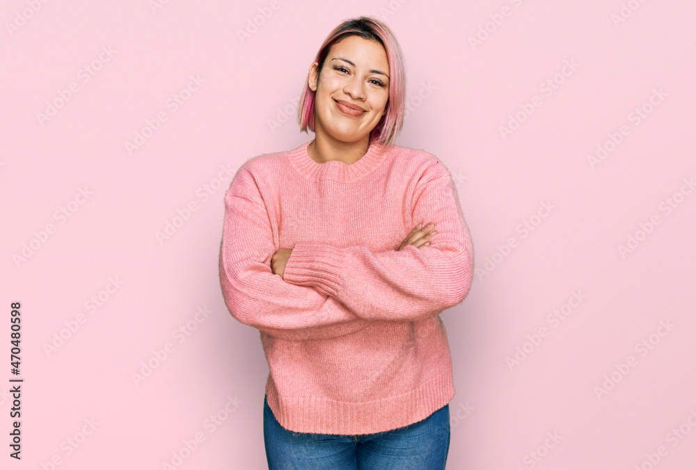 Hispanic woman with pink hair wearing casual winter sweater happy face smiling with crossed arms looking at the camera. positive person.