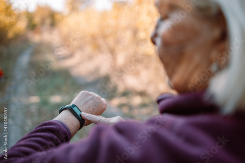 Active sport young runner checking heart rate after run outdoors in city autumn park. Healthy lifestyle concept. photo