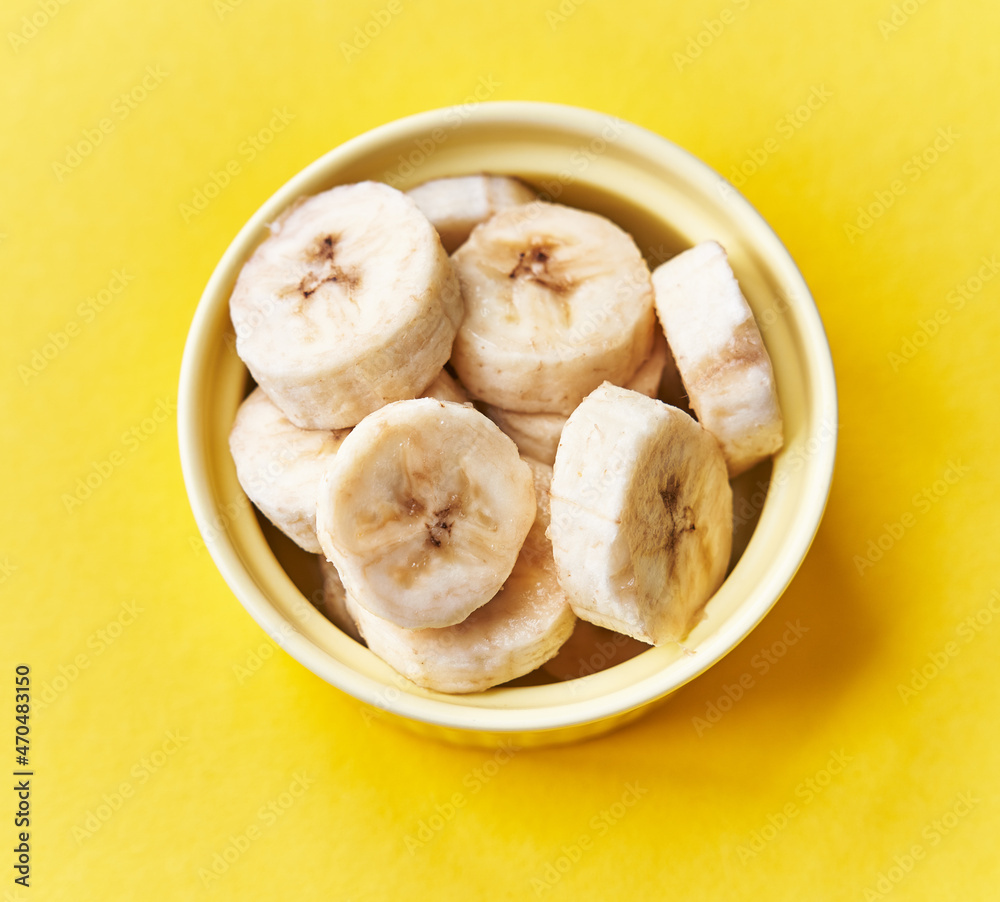 Bowl of slices of banana on a yellow background Bowl of slices of banana on a yellow background