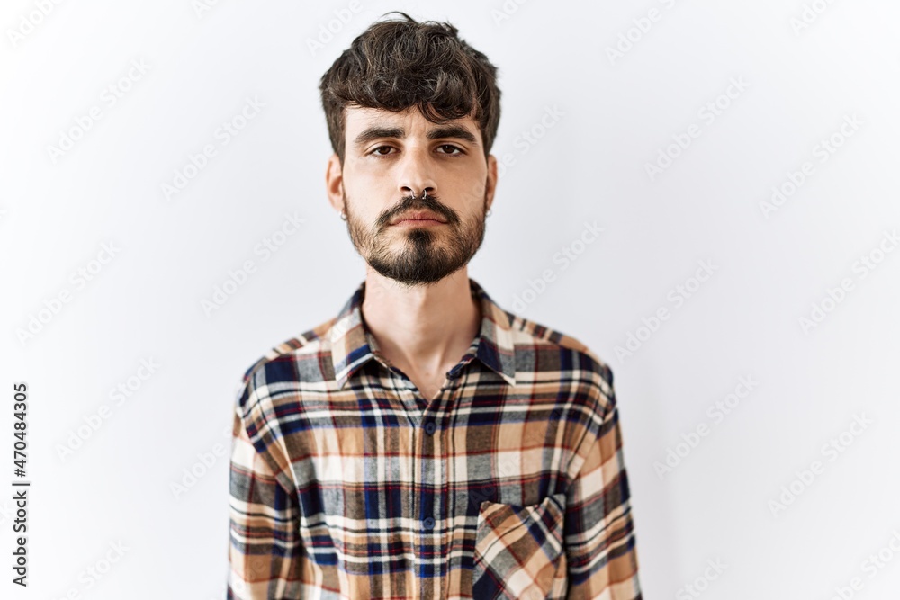 Hispanic man with beard standing over isolated background relaxed with serious expression on face. simple and natural looking at the camera.