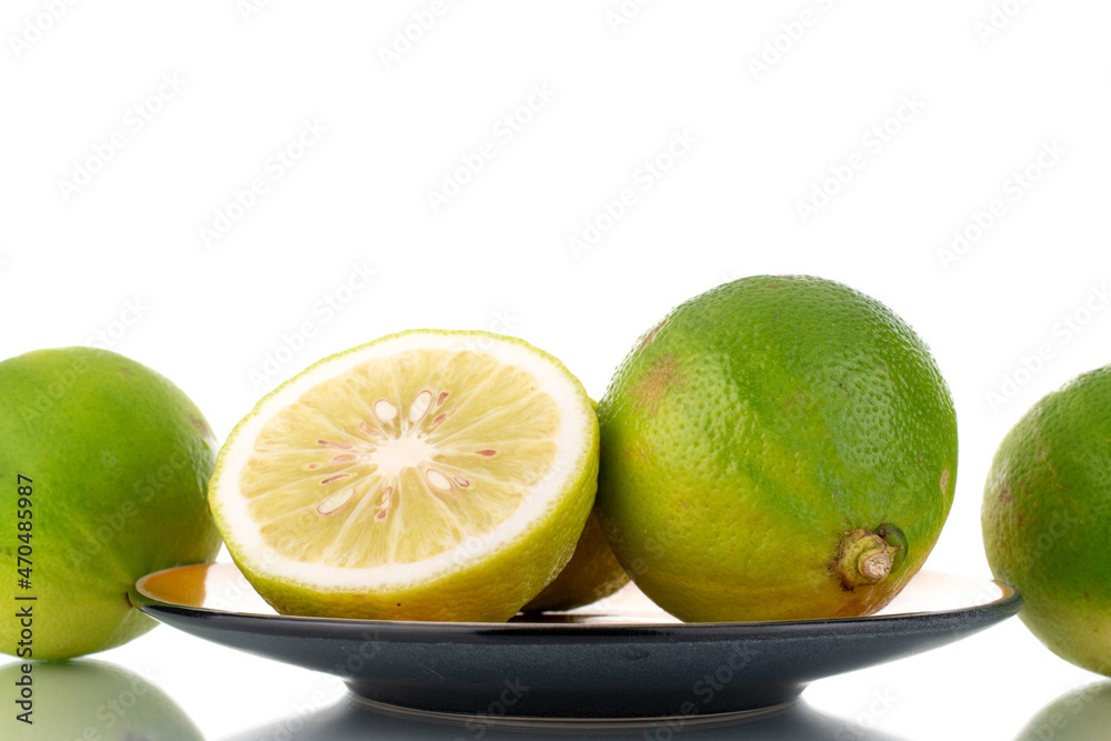 One half and several whole fragrant ripe bergamots on a ceramic saucer, close-up, isolated on white.