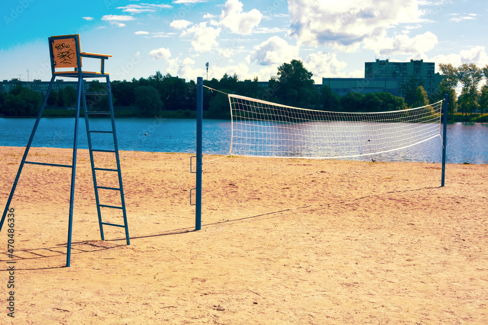 A stretched volleyball net on a sandy sports field near the river on a sunny summer day