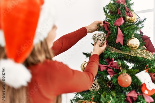 Young caucasian woman on back view decorating christmas tree at home