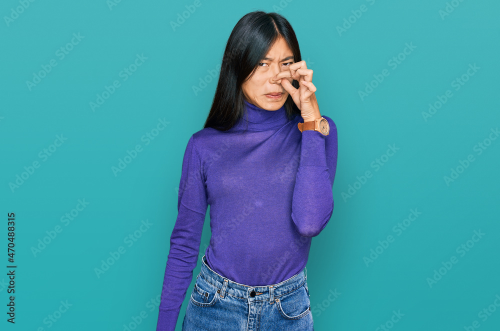 Beautiful young asian woman wearing casual clothes smelling something