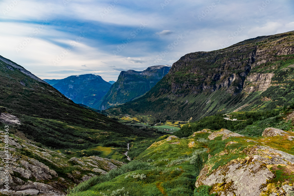 View from the road on a the valley between beautiful Norwegian mountains against dramatic cloudy sky View from the road on a the valley between beautiful Norwegian mountains against dramatic cloudy sky