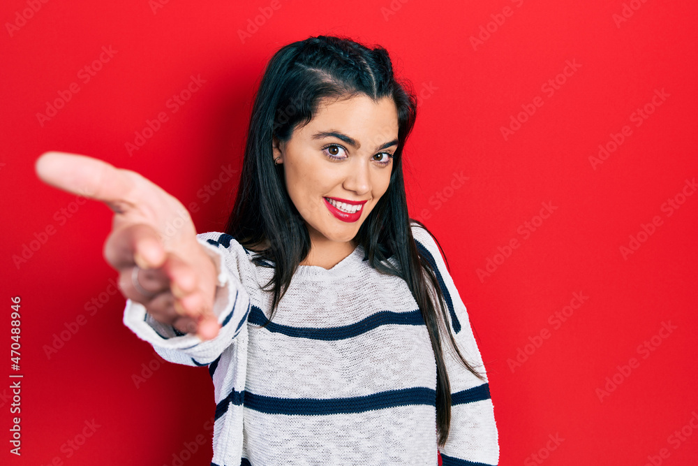 Young hispanic girl wearing casual clothes smiling friendly offering handshake as greeting and welcoming. successful business. Young hispanic girl wearing casual clothes smiling friendly offering handshake as greeting and welcoming. successful business.