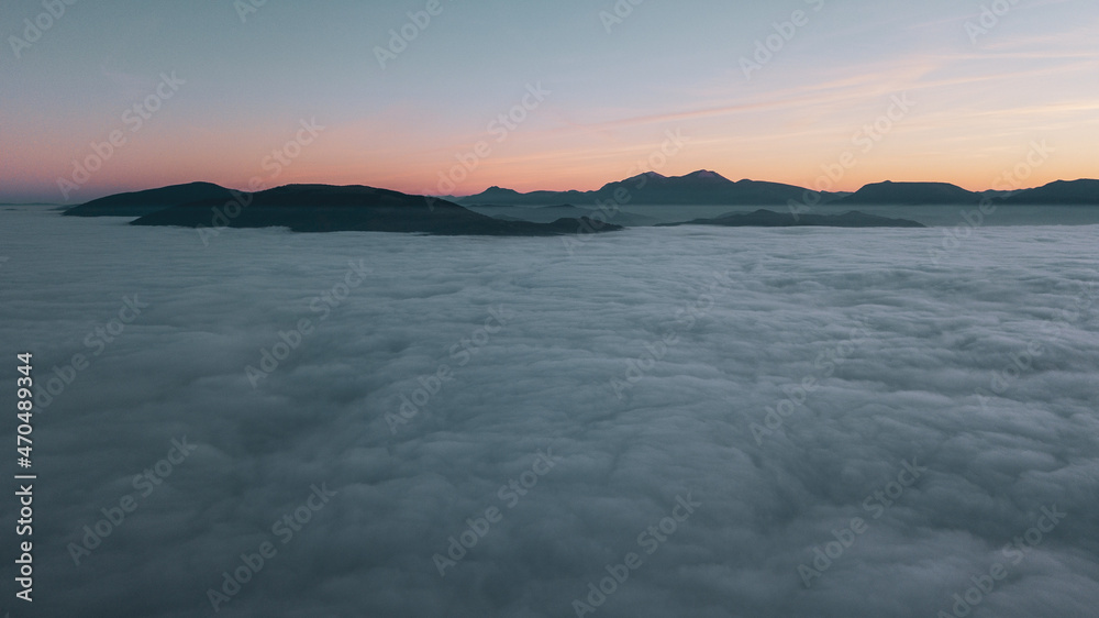 Italy November 2021: aerial view of mountains with fog below in autumn season at sunset
