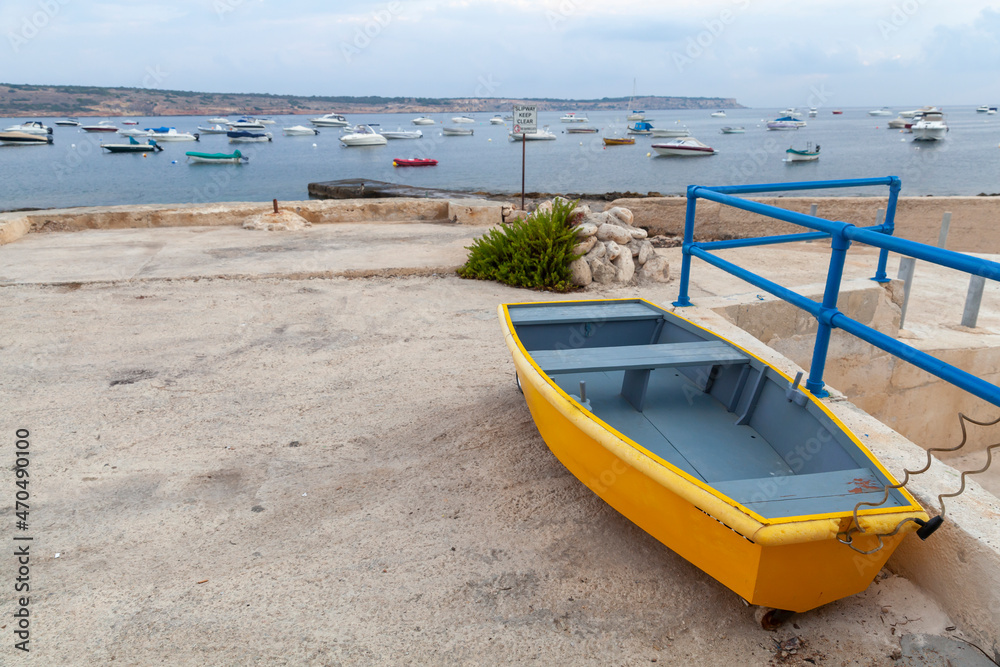 Small yellow boat lays on the ground in Mellieha, Malta