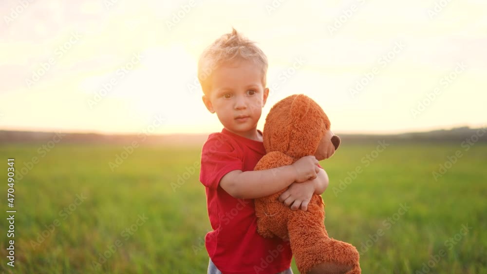 portrait of a baby boy with a toy teddy bear in his hands on nature in ...