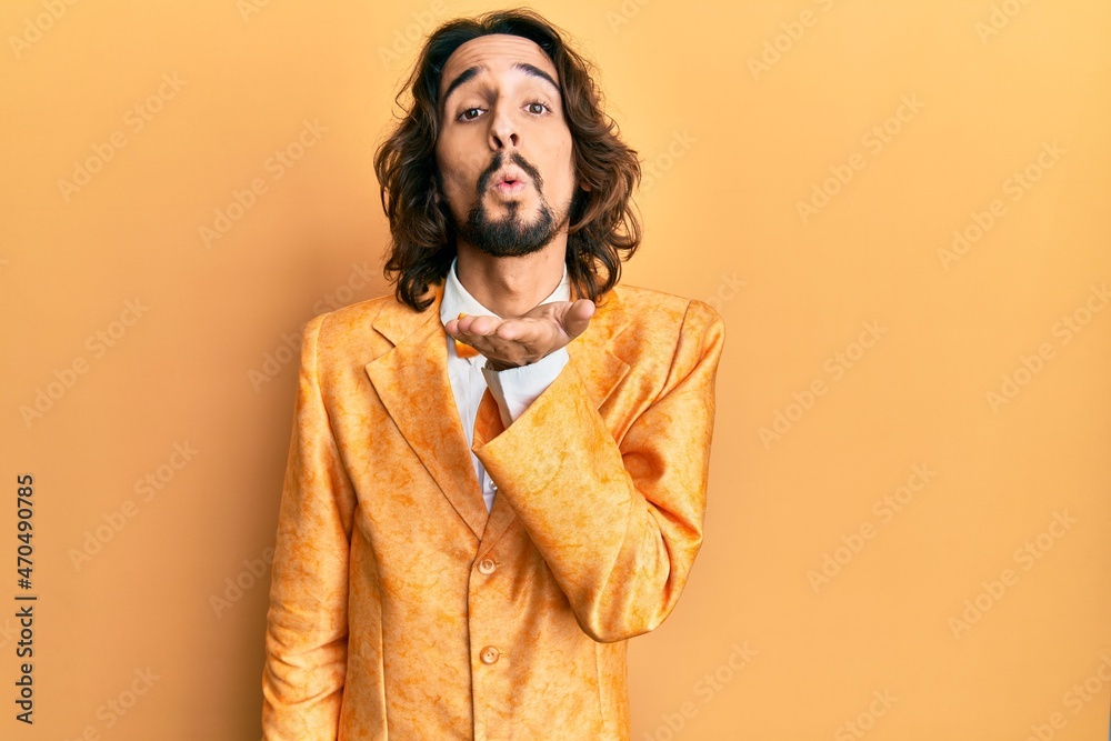 Young hispanic man wearing hipster elegant look looking at the camera blowing a kiss with hand on air being lovely and sexy. love expression.