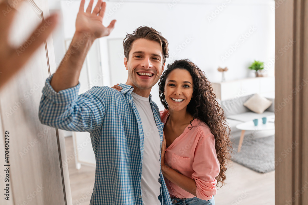 Happy couple inviting people to enter home, giving high five Happy couple inviting people to enter home, giving high five
