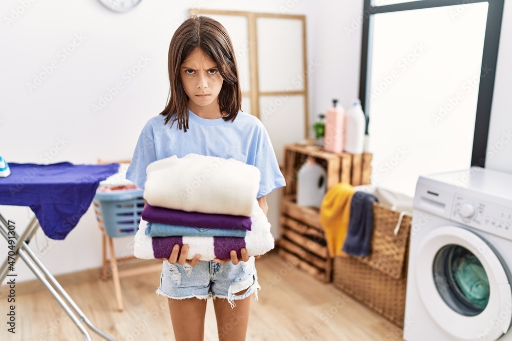 Young hispanic girl holding folded laundry skeptic and nervous, frowning upset because of problem. negative person. Young hispanic girl holding folded laundry skeptic and nervous, frowning upset because of problem. negative person.