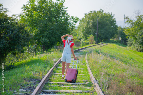 a traveler in a hat walks with a suitcase along the paths © Vyacheslav