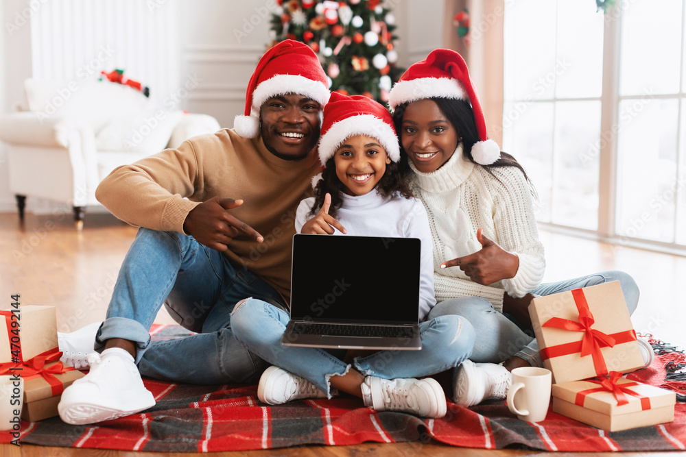 Happy festive black family showing laptop with empty screen, mockup Happy festive black family showing laptop with empty screen, mockup