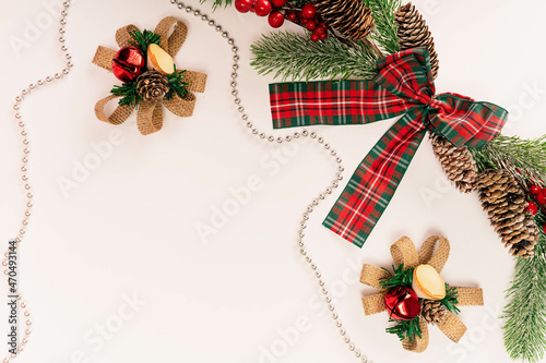 Fir branch with cones with a red-green bow and decorations on a light background