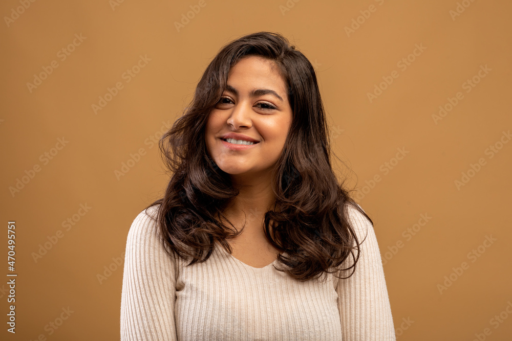 Natural beauty. Happy arab lady with wavy hair and perfect smile posing over brown background, looking at camera Natural beauty. Happy arab lady with wavy hair and perfect smile posing over brown background, looking at camera