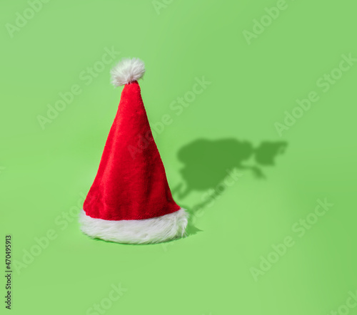 Grinch shadow stealing Christmas behind Santa's cap on bright green background. photo