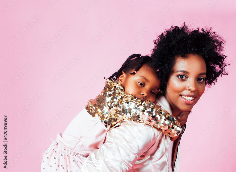young pretty african-american mother with little cute daughter hugging, happy smiling on pink background, lifestyle modern people concept