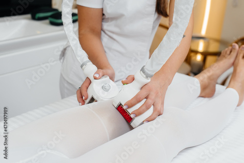 A young woman in a white suit, undergoing cosmetic LPG massage and laser lipolysis, close-up. Cosmetic procedure, in a medical center. Anti-cellulite procedures. Close-up.