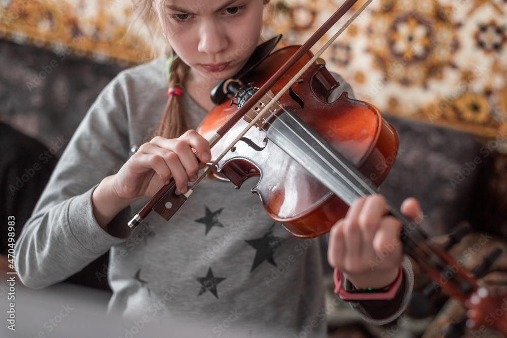 Beautiful teenager girl rehearses the violin at home. Music lessons in isolation during quarantine. Beautiful teenager girl rehearses the violin at home. Music lessons in isolation during quarantine.