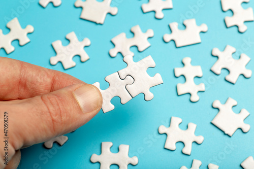  Puzzle pieces are connected. White puzzle pieces in hand on a blue background. Business, partner, solution, alliance, union concept.