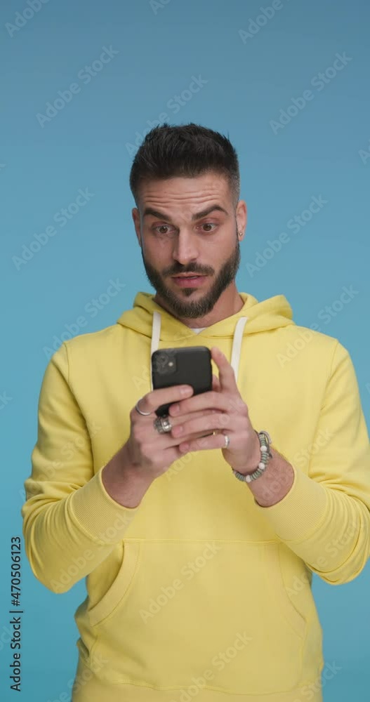 handsome casual man texting on his phone when suddenly something surprised him in a good way handsome casual man texting on his phone when suddenly something surprised him in a good way