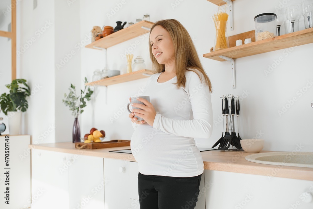 Young pregnant woman drinking tea in kitchen Young pregnant woman drinking tea in kitchen
