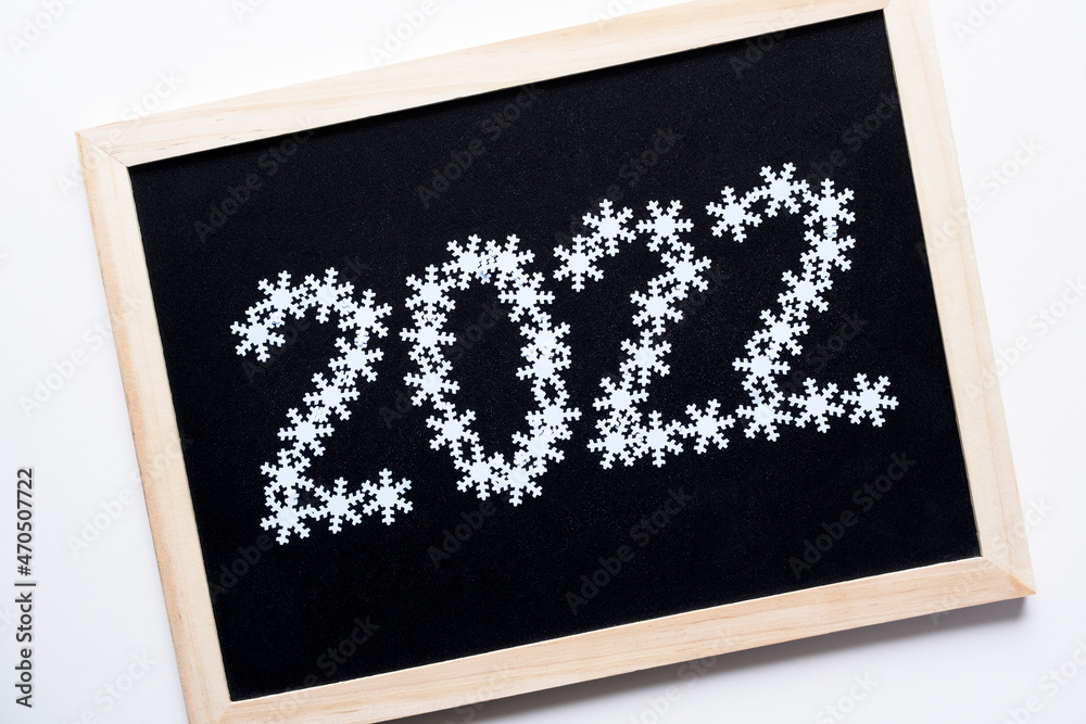2022 inscription made of beautiful white snowflakes. On a dark, black chalkboard background. New Year and Christmas mood concept 2022 inscription made of beautiful white snowflakes. On a dark, black chalkboard background. New Year and Christmas mood concept