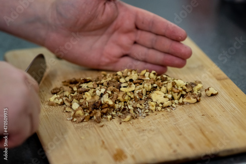 man cuts walnuts for a pie. Cooking at home.