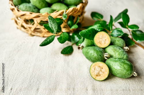 Fototapeta Naklejka Na Ścianę i Meble -  Fresh green feijoa fruits on linen tablecloth. Acca sellowiana berries of the guava family. Vitamin C, Healthy eating. Selective focus.