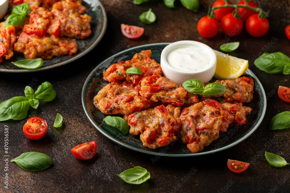 Greek tomato fritters, tomatokeftedes served with yogurt on plate. Greek tomato fritters, tomatokeftedes served with yogurt on plate.