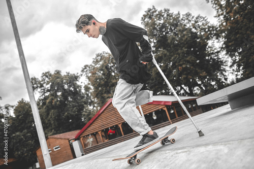 Profile of guy on crutches riding skateboard