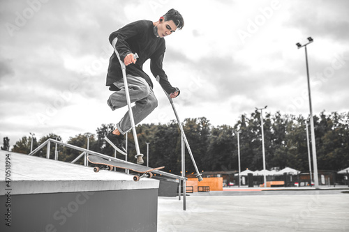Guy on crutches jumping down from hill on skateboard
