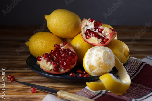 Still life with lemons and pomegranate on a plate.