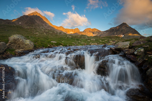 Mountain river in the Italian Alps in the background Mount Gaviola and Corno dei Tre Signori during sunset, Stelvio National Park, Lombardy, Italy