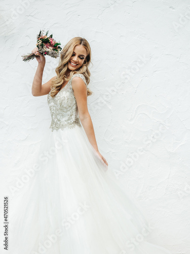 Happy bride with bouquet near wall photo