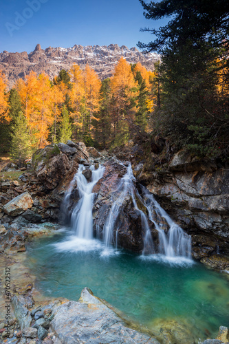 Waterfall in the heart of the forest during autumn season, Swiss Alps, Graubunden, Switzerland