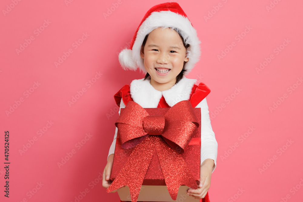 smiling young girl holding gift box stand in front of pink background