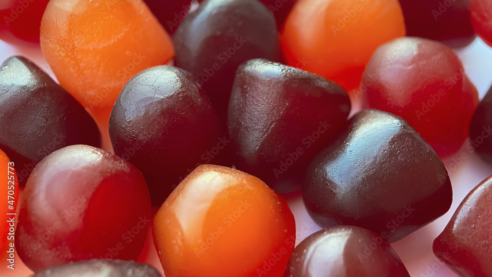 Selective focus.Close-up texture of red, orange and purple multivitamin gummies on white background Selective focus.Close-up texture of red, orange and purple multivitamin gummies on white background
